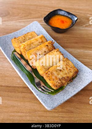 Scheiben typischer chinesischer Rettichkuchen serviert auf einem Bananenblattteller mit Chilisauce Stockfoto