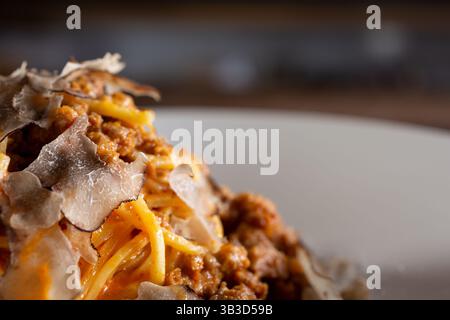 Ein Blick aus der Nähe auf einen Hügel mit Spaghetti-Pasta mit Fleischsoße und schwarzem Trüffelbelag. Stockfoto