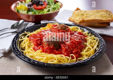 Blick auf ein Abendessen mit Spaghetti und Fleischbällchen, mit einem Salat und Knoblauchbrot. Stockfoto