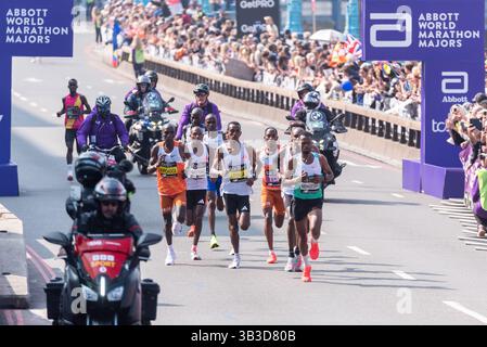 Elite Männer führende Athleten, die 2025 beim TCS London Marathon antreten, fahren durch Tower Hill, London, Großbritannien, mit Sicherheits- und Medienreitern Stockfoto