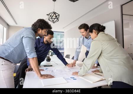 Das Team prüft Finanzberichte und analysiert den Umsatz, der am Konferenztisch gesammelt wurde Stockfoto