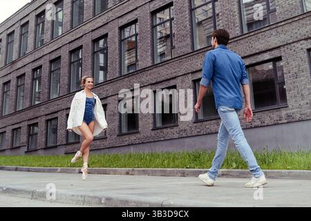Ein verliebter Partner trifft auf eine Ballerina auf einer Straße, während er an einem Sommertag durch die Stadt spaziert Stockfoto
