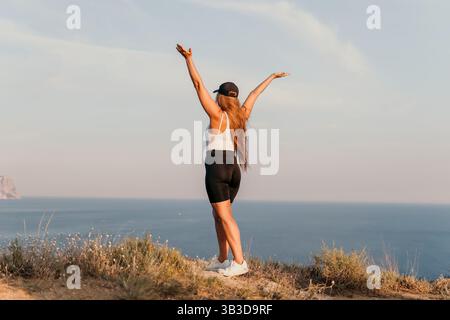 Frau hebt ihre Arme in Victory on a Cliffside Stockfoto