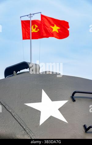 Rote Fahnen mit kommunistischen Symbolen flattern auf einem Fahnenmast über einem historischen Panzerturm Stockfoto