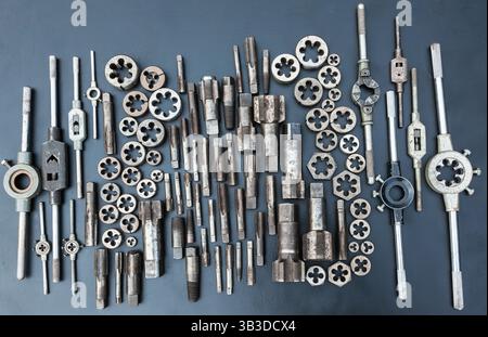 Gewindebohrer, Matrizen und Schraubenschlüssel für Gewindebohrer und Matrizen auf schwarzem Hintergrund. Manuelles Gewindewerkzeug. Stockfoto