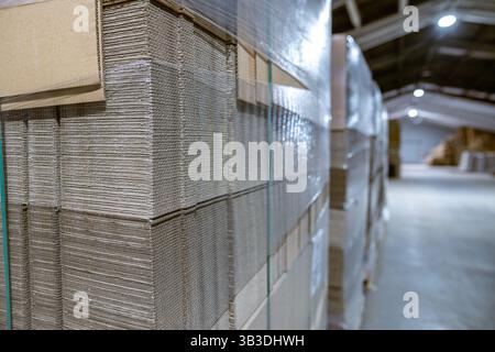 Faltbare Pappkartons. Lochbleche aus Wellpappe ein Stapel auf Paletten. Verpackung von Fertigerzeugnissen in der industriellen Produktion. Stockfoto