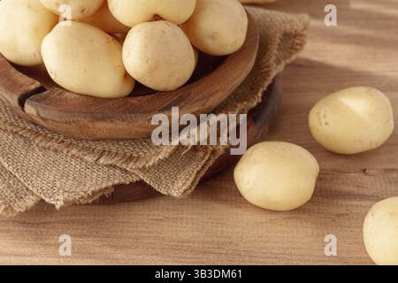 Gekochte neue Kartoffeln, in einer Holzschale, auf einem rustikalen Tisch, natürliches Licht, keine Leute Stockfoto