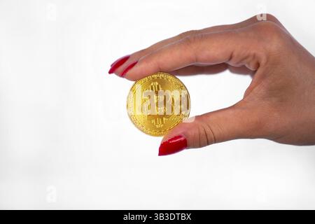 Virtuelle cryptocurrency Geld Bitcoin goldene Münze in der rechten Hand einer Frau mit rotem Nagellack. Die Zukunft des Geldes. Auf einem weißen backgroun Isoliert Stockfoto