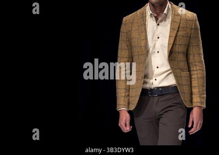 Männliches Modell geht der Start- und Landebahn in braunen Anzug während einer Modenschau. Fashion Catwalk Ereignis zeigt neue Sammlung von Kleidung. Ein Modell auf einer b isoliert Stockfoto