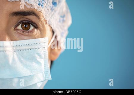 Krankenschwester mit blauer Schutzkappe und chirurgischer Gesichtsmaske während der Coronavirus-Krankheit COVID-19-Epidemie. Nahaufnahme von Hochformat mit einem Sing Stockfoto