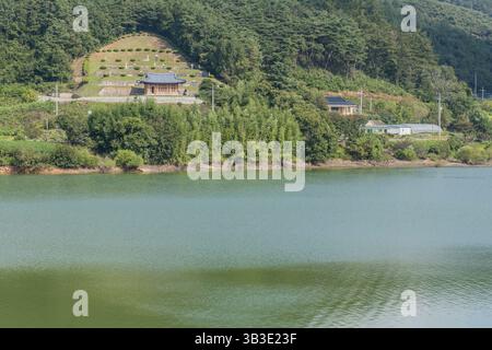 Cheongyang-Gun, Südkorea, 2. Oktober 2020: Kleiner ländlicher Friedhof am Hang mit See im Vordergrund, Asien Stockfoto