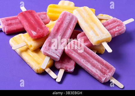 Rote Erdbeere und gelbe Stiele auf violettem Hintergrund Stockfoto