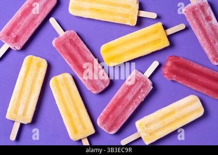 Rote Erdbeere und gelbe Stiele auf violettem Hintergrund Stockfoto