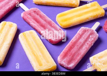 Rote Erdbeere und gelbe Stiele auf violettem Hintergrund Stockfoto