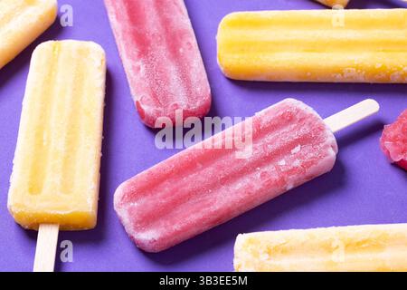 Rote Erdbeere und gelbe Stiele auf violettem Hintergrund Stockfoto