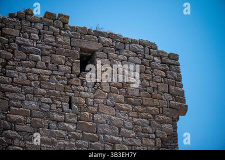 Aus nächster Nähe sehen Sie eine alte römische Steinmauer, die verwitterte Texturen, kompliziertes Mauerwerk und zeitlose Handwerkskunst römischer Architektur zeigt Stockfoto