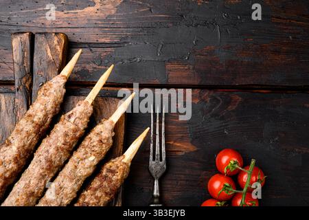 Schaschlik auf einem Stock, vom Hammelfleisch auf dem Boden, auf Servierbrett, auf altem dunklem Holztischhintergrund, Draufsicht flach, mit Kopierraum für Stockfoto