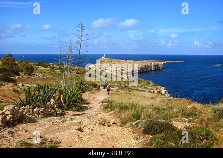 Malerischer Spaziergang entlang eines felsigen Touristenpfads mit wilden Pflanzen und Klippen, mit Blick auf das Mittelmeer unter klarem Himmel. Stockfoto