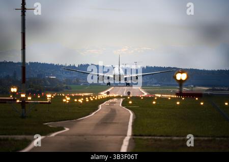 Kommerzielles Flugzeug von hinten gesehen, kurz bevor es auf der Landebahn landet. Bodennaher Blickwinkel, Super-Tele-Aufnahme, früh morgens Stockfoto