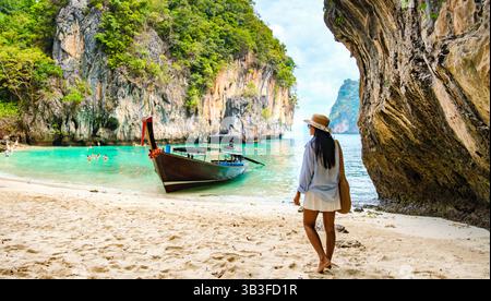 Besucher sonnen sich in der Wärme der Sonne, umgeben von atemberaubenden Kalksteinklippen und üppigem Grün. Reisende genießen die ruhige Atmosphäre auf dem weichen Sand der Insel Koh Lao Lading. Stockfoto
