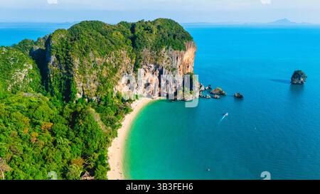 Sanfter goldener Sand verbindet sich mit dem kristallklaren Wasser des Railay Beach. Hoch aufragende Klippen und üppiges Grün schaffen eine ruhige Kulisse für Abenteuerlustige und Entspannungsbegeisterte in Krabi Thailand. Stockfoto