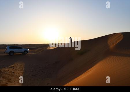 Rub Al Khali Wüste, Sultanat von Oman. Geländewagen im Geländewagen in der Wüste Wahiba Sands bei Sonnenaufgang, Arabische Halbinsel. Die Touristenfrau macht ein Foto von La Stockfoto