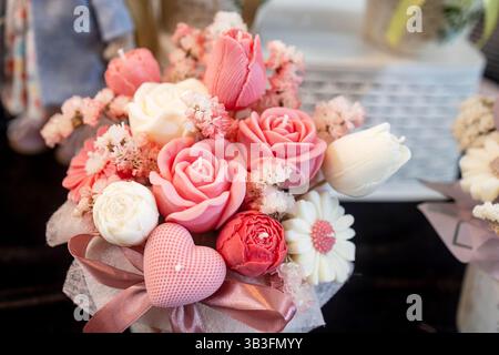 Ein bezaubernder Strauß handgefertigter Seifenkerzen in Form von Rosen und Tulpen, gebunden mit einem rosa Band Stockfoto