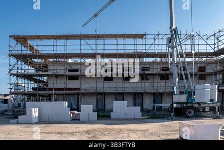 Eine lebhafte Baustelle in den Niederlanden zeigt neu gebaute Familienhäuser. Die Arbeiter sind damit beschäftigt, moderne Häuser zu errichten, mit Gerüsten und Maschinen, um ein einladendes Vorstadtviertel zu schaffen. Stockfoto