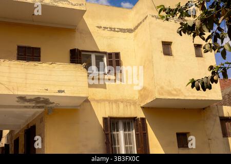 Altes Wohngebäude in Ägypten mit gelben Wänden und braunen Fensterläden Stockfoto