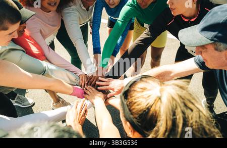 Eine Gruppe von Läufern vereint sich in einer kleinen Gruppe, die Teamarbeit und Kameradschaft verkörpert. Sie bereiten sich auf einen Marathon vor und demonstrieren Einheit und Moti Stockfoto