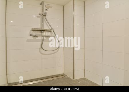 Eine elegante und minimalistische Duschkabine mit weiß gefliesten Wänden und modernem Duschkopf. Das Design betont Einfachheit und Sauberkeit. Stockfoto