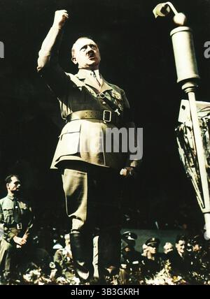 Adolf Hitler sprach zu einer Nazi-Kundgebung in Nürnberg, Deutschland, 1930er Jahre Die NSDAP hielt von 1927 bis 1938 jährlich politische Kundgebungen in Nürnberg ab. Nachdem die Nazis 1933 die Macht beanspruchten, wurden die Kundgebungen zu massiven staatlichen Propagandaveranstaltungen. Hitlers Stellvertreter, Rudolf Hess, ist unten links auf dem Bild. (Farbiger Schwarzweiß-Druck). Stockfoto