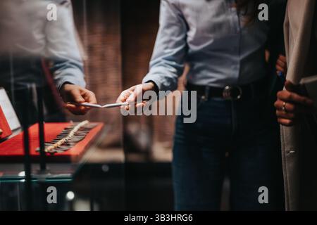 Zwei Personen untersuchen Exponate in einem Museum, wobei einer ein Objekt übergibt. Stockfoto