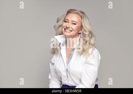 Kopfporträt einer lächelnden Reifen Frau auf grauem Hintergrund Stockfoto