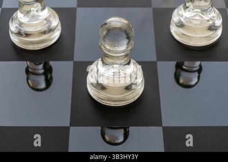 Glaspflöckchen auf einem Glasschachbrett Stockfoto