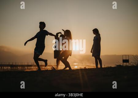Gruppe von Freunden, die gemeinsam einen wunderschönen Sonnenuntergang am Strand genießen Stockfoto