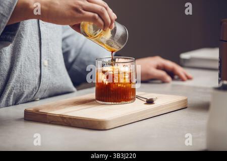 Frisch gebrühten Kaffee in Glas für einen eisgekühlten Americano in der modernen Küche eingießen Stockfoto