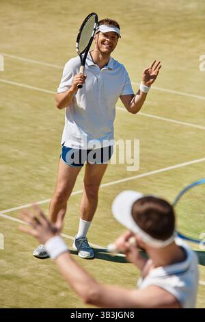 Zwei Männer teilen sich fröhliche Momente, während sie an einem sonnigen Sommertag Tennis spielen. Stockfoto