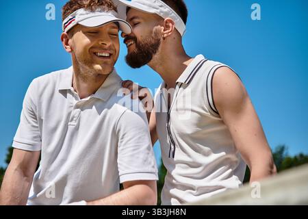Zwei Männer teilen fröhliche Momente beim Tennisspielen an einem sonnigen Sommertag. Stockfoto