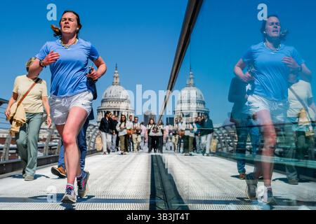 London, Großbritannien. April 2025. Nach dem Marathon gibt es auf der Millennium Bridge zahlreiche Jogger aller Formen und Größen. Eine Mini-Hitzewelle im Frühsommer führt zu warmem, sonnigem Wetter und die Außenbereiche in London sind sehr voll. Guy Bell/Alamy Live News Stockfoto