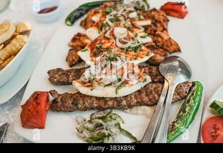 Lamm-Hühnchen-Kebab auf Spießen. Gegrilltes Fleisch und Gemüse mit Pizza-Pita-Brot. Shish Kebab, Zwiebeln, Tomaten. Traditionelle Küche des Nahen Ostens o Stockfoto