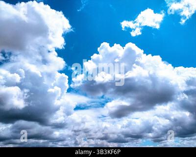 Dramatischer Himmel voller heller, geschwollener Wolken vor einem leuchtend blauen Hintergrund. Weckt Gefühle des Friedens, der Möglichkeit und des Staunens. Ideal für den Hintergrund Stockfoto