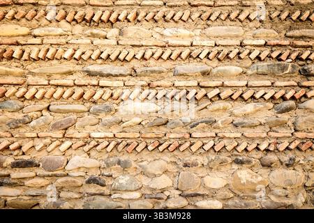 Detaillierter Blick auf eine historische georgianische Mauer, die mit Steinen und Ziegeln in dekorativen diagonalen Schichten erbaut wurde und alte Bautraditionen widerspiegelt Stockfoto