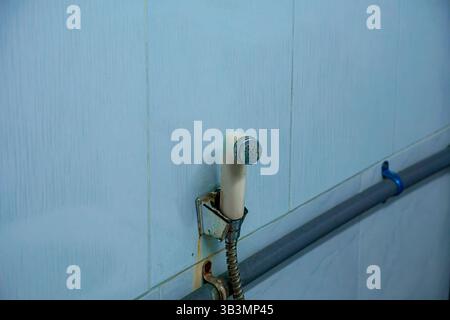 Handgehaltenes Bidet-Sprühgerät aus Kunststoff an einer gefliesten Badezimmerwand Stockfoto