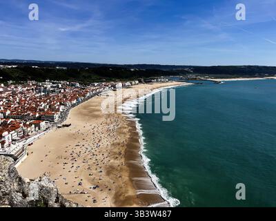 Nazare Beach mit goldenem Sand, blauem Meer und umliegender malerischer Landschaft. Stockfoto