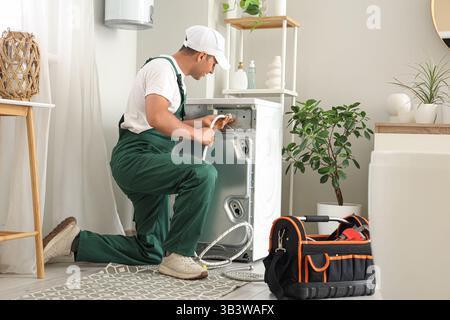 Männliche Klempner, die Waschmaschine im Badezimmer befestigen Stockfoto