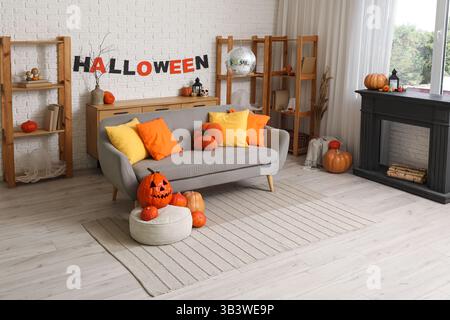 Das Innere des stilvollen Wohnzimmers mit Sofa, Kamin, Kürbissen und Discokugel ist für Halloween-Party dekoriert Stockfoto