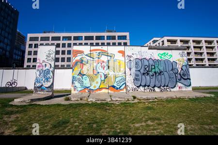 Reste der ehemaligen Berliner Mauer mit Graffiti vor frisch grundierten Sektionen in der East Side Gallery. Stockfoto