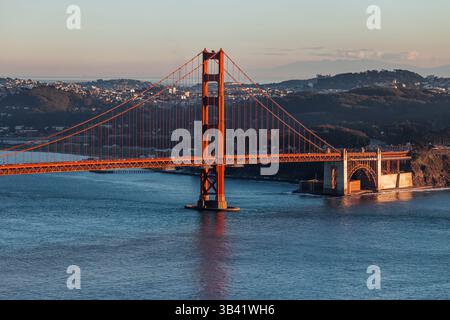 Die Golden Gate Bridge steht bei Sonnenuntergang über der Bucht von San Francisco mit klarem Himmel und weit entfernten Hügeln Stockfoto
