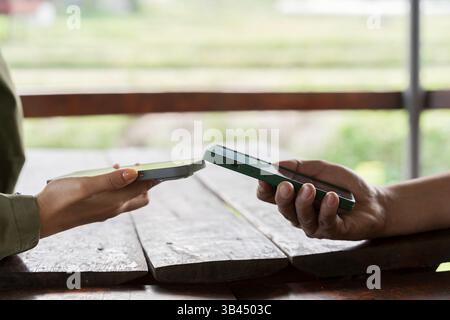 Zwei Telefone in Frauenhänden übertragen Daten über bluetooth miteinander. Nahaufnahme. Junge Freunde tippen auf Smartphones, um schnell einige Informationen weiterzugeben Stockfoto